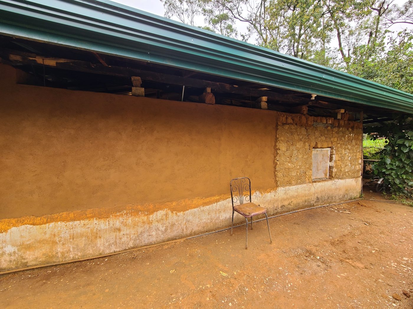 A wall with fresh coloured lime plaster beside a section of old stone and adobe