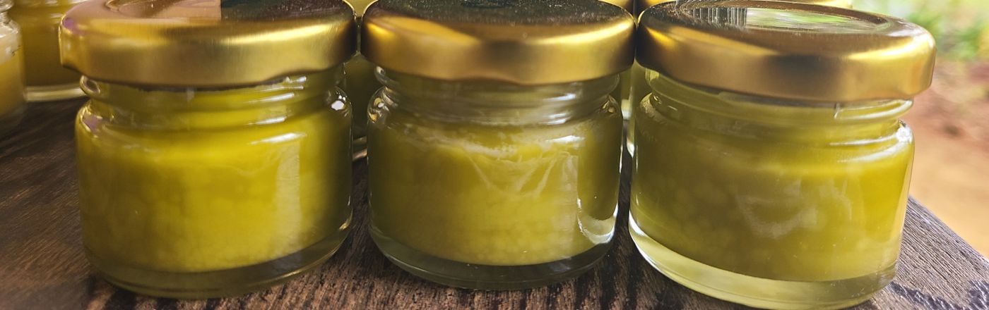 A table of freshly set salve jars, outdoors at the farm